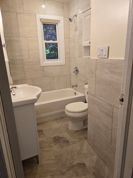 Renovated bathroom with grey tile surround and new tub